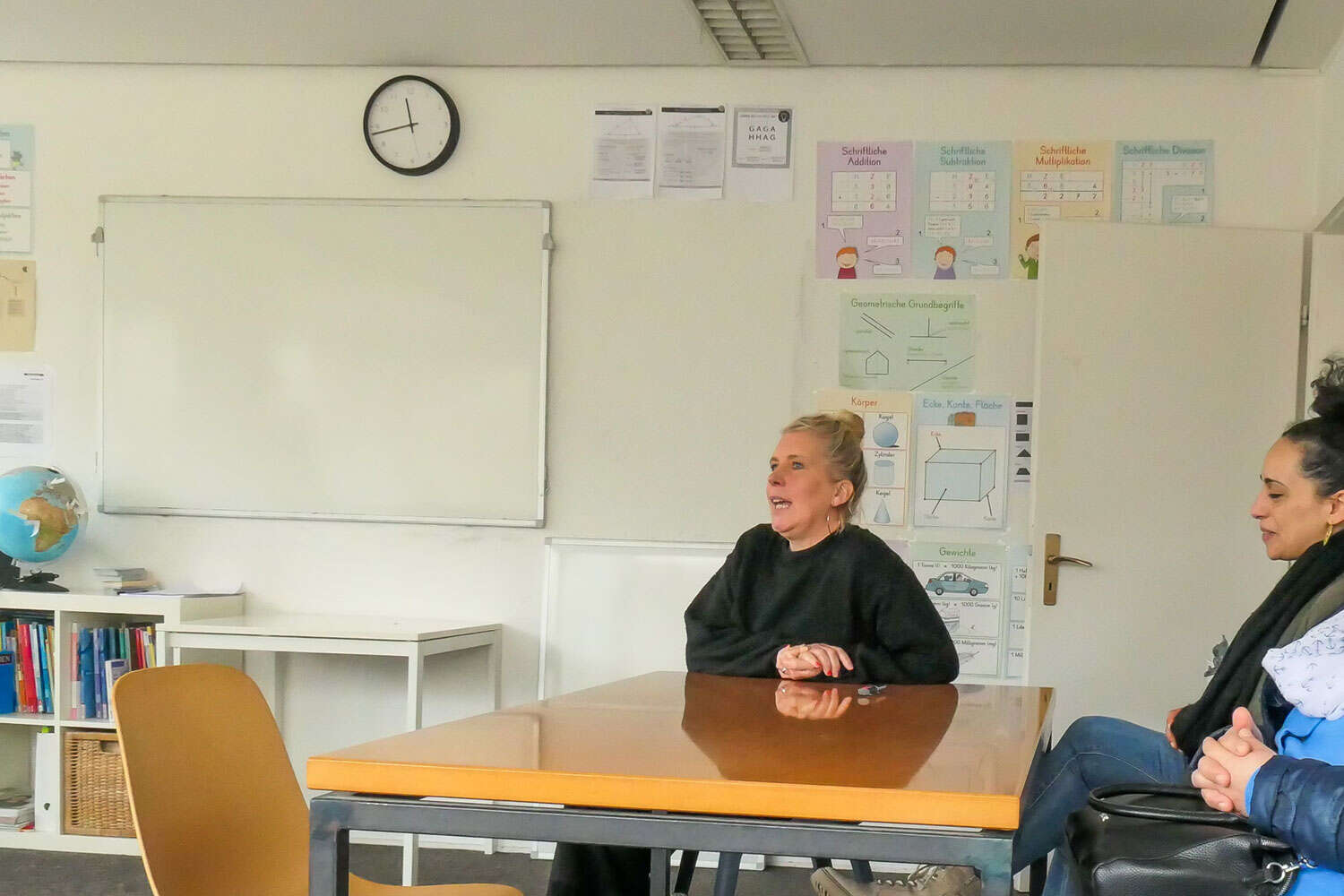 Frau sitzt am Tisch und spricht in die Rund